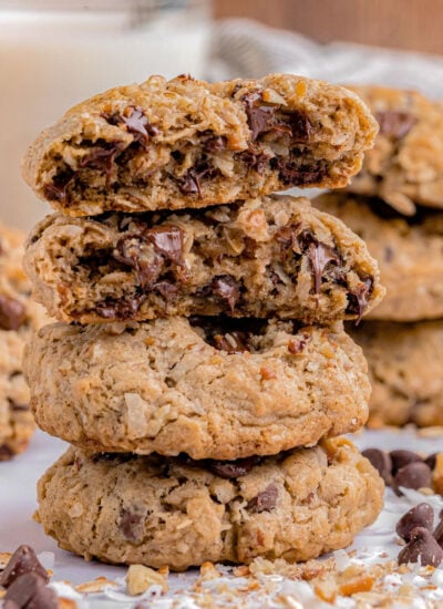 three cowboy cookies stacked on top of each other with the top cookie split in half so you can see the melted chocolate.