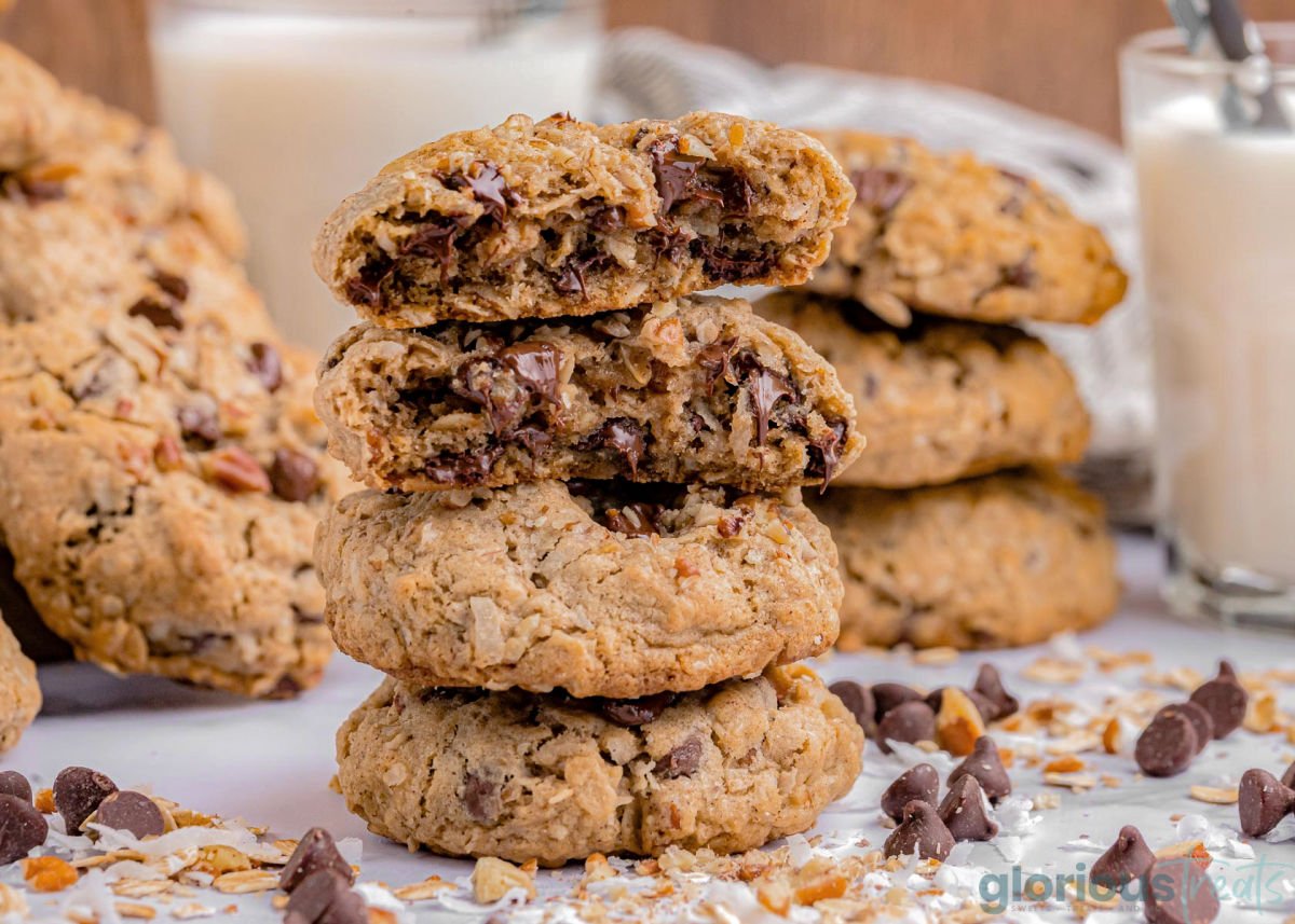 three cowboy cookies stacked on top of each other with the top cookie split in half so you can see the melted chocolate.