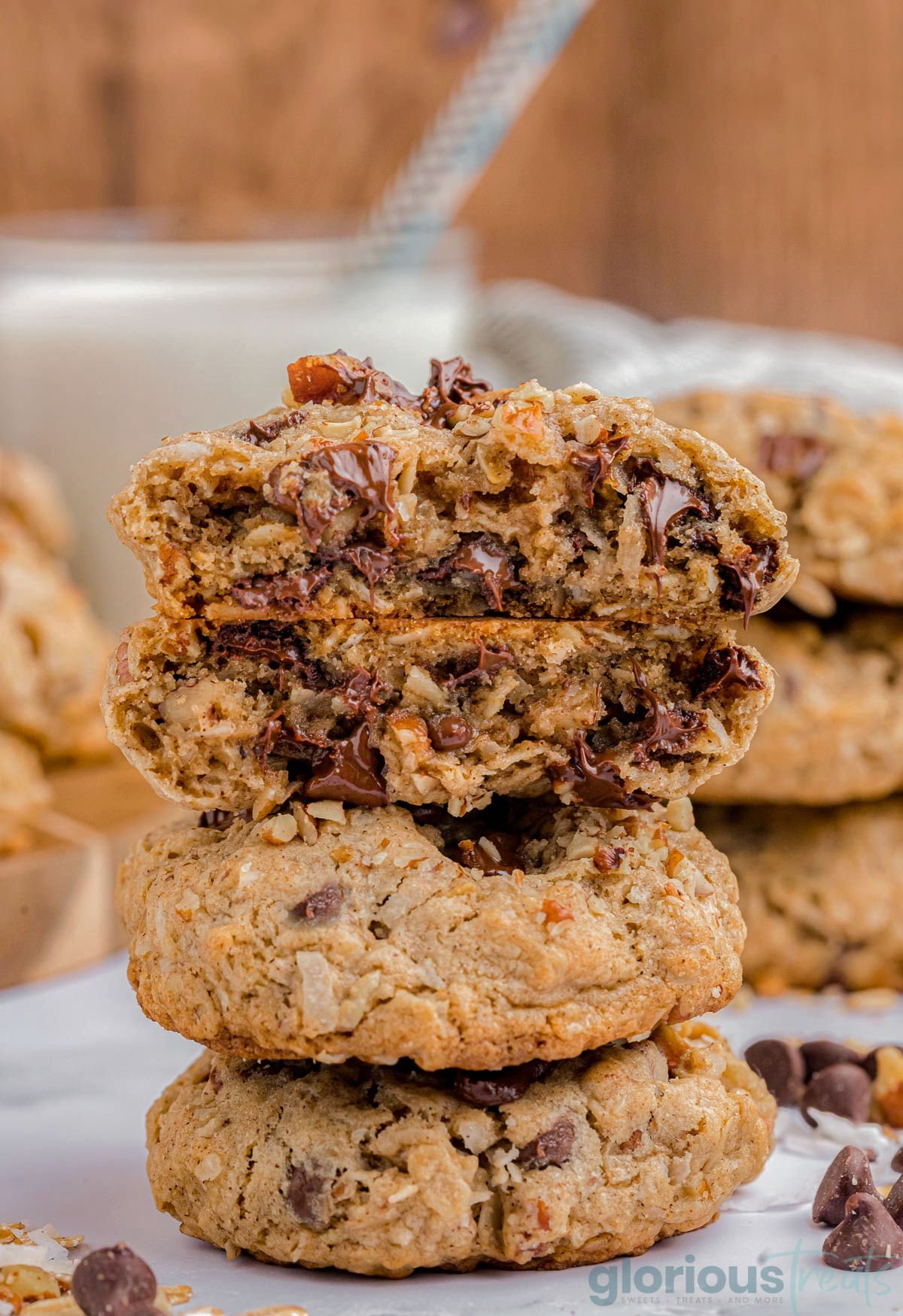 three cowboy cookies stacked on top of each other with the top cookie split in half so you can see the melted chocolate.