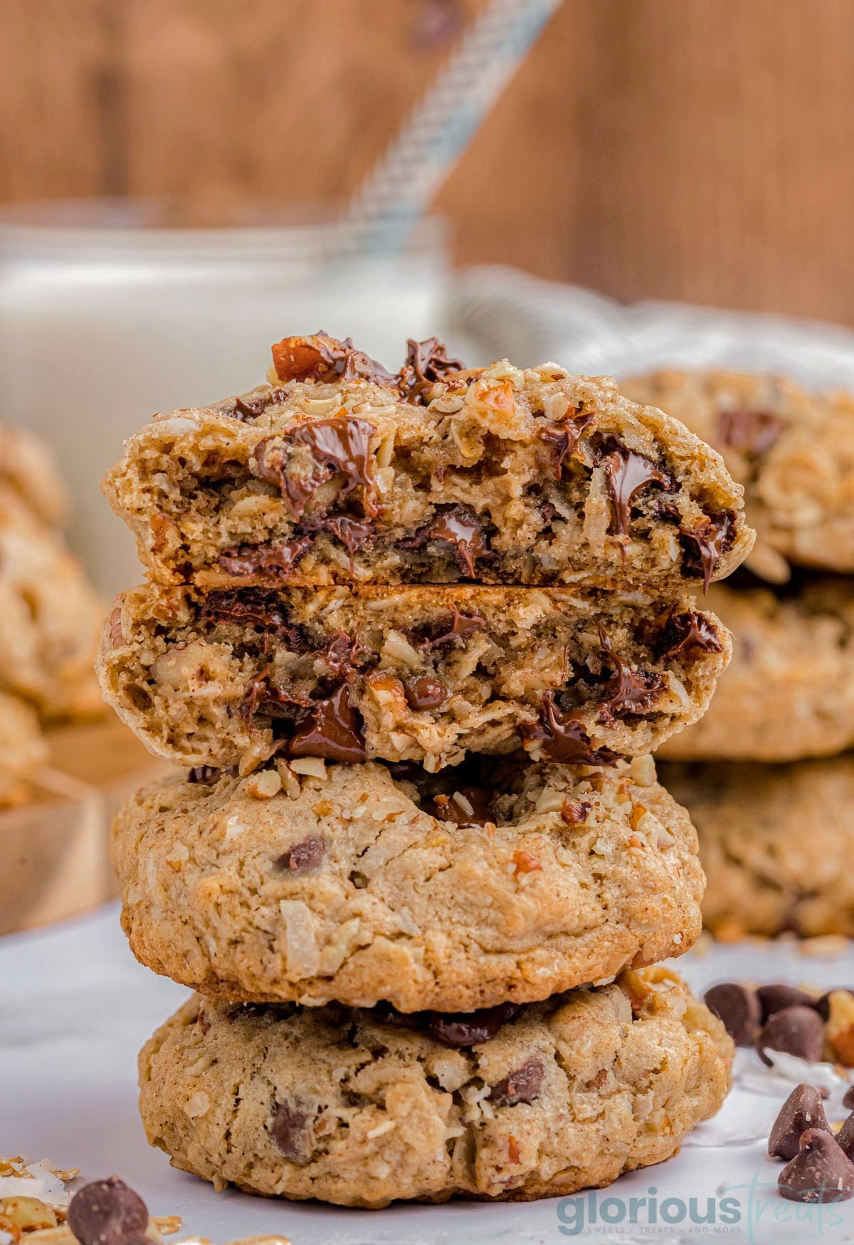 three cowboy cookies stacked on top of each other with the top cookie split in half so you can see the melted chocolate. 