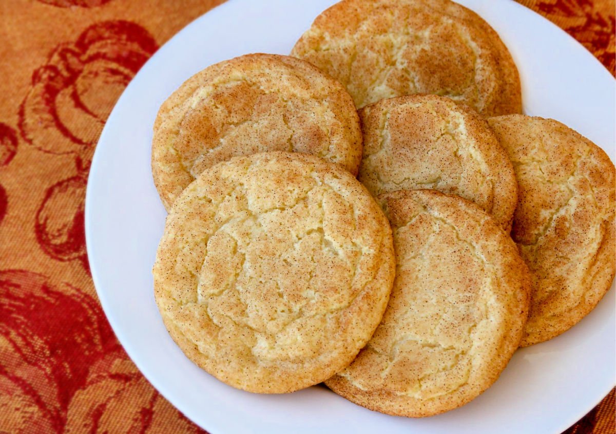 six cookies on a white plate with red and orange fabric underneath