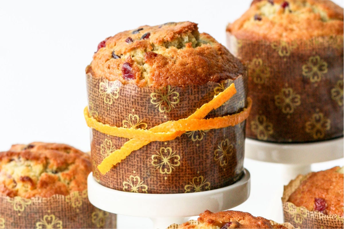 close up of cranberry orange muffin recipe on cupcake stand with more muffins in background