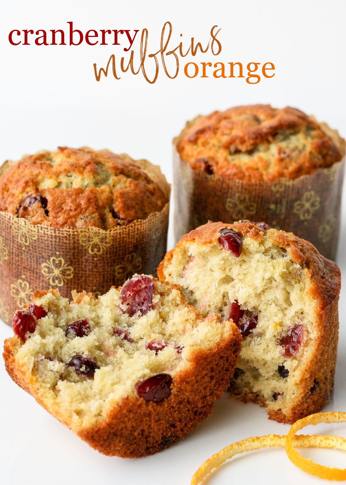 cranberry orange muffin split in half with orange peel text two whole muffins in background