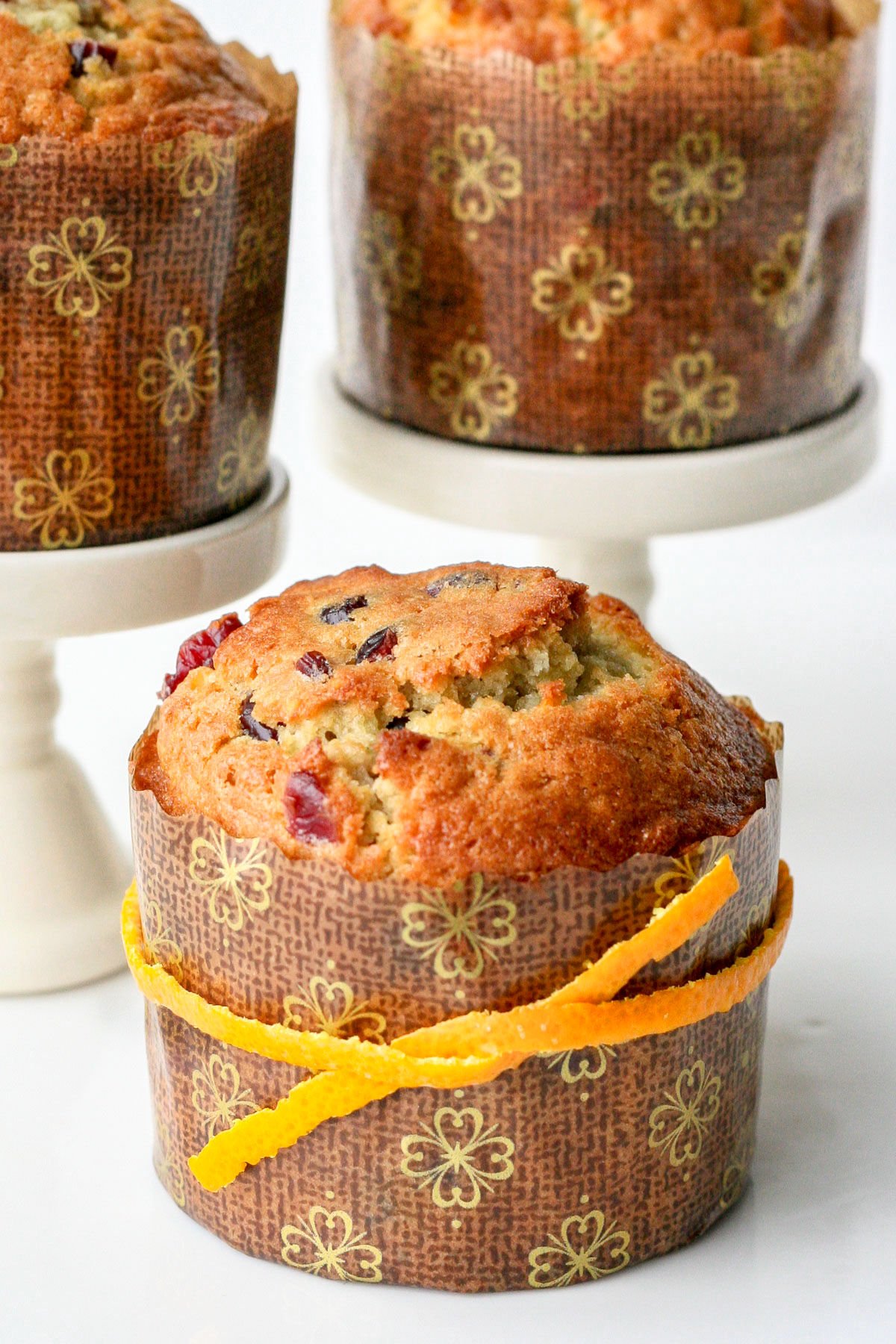 single cranberry orange muffin in paper liner with orange peel tied around it