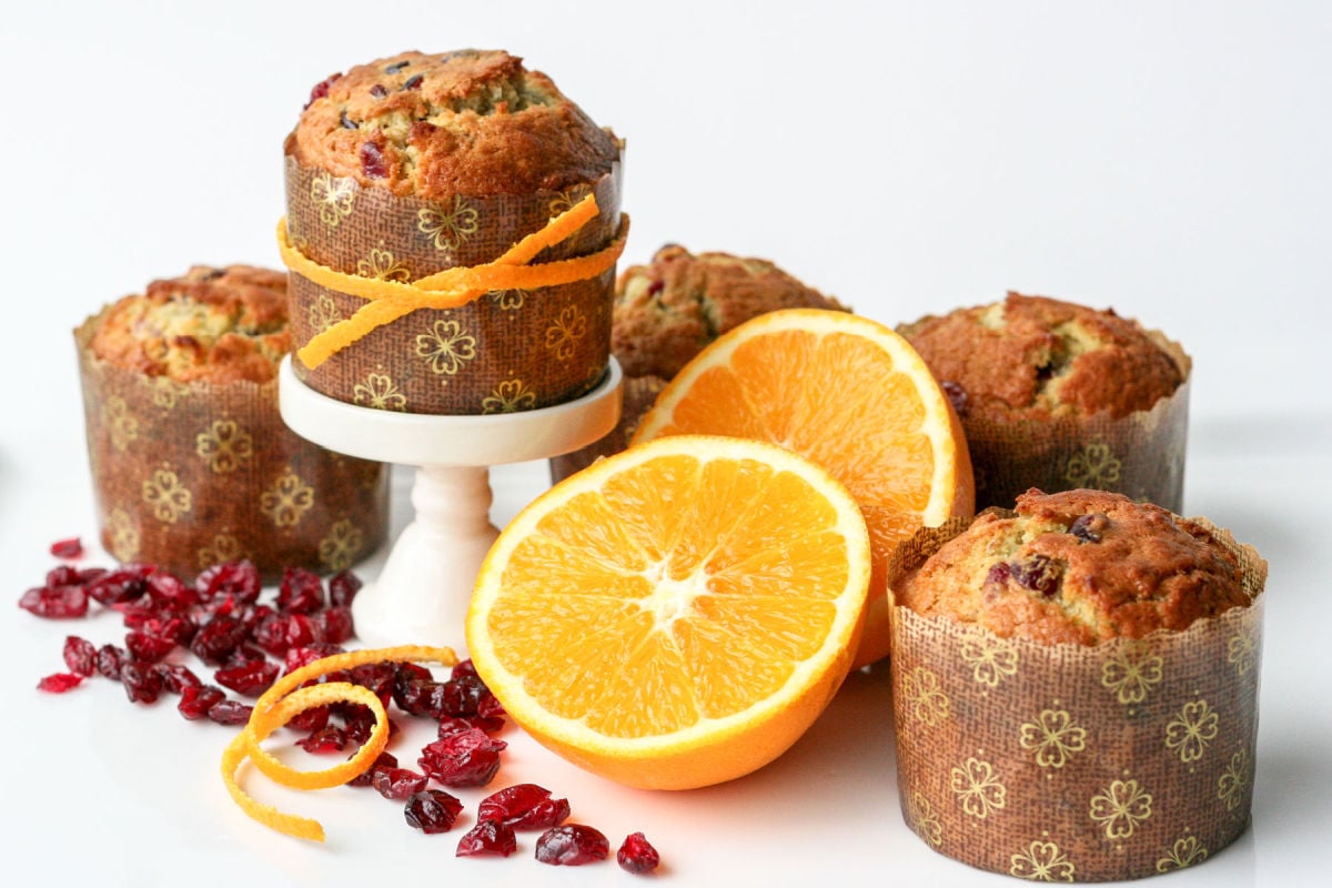 cranberry orange muffins with orange half and peels and dried cranberries scattered about