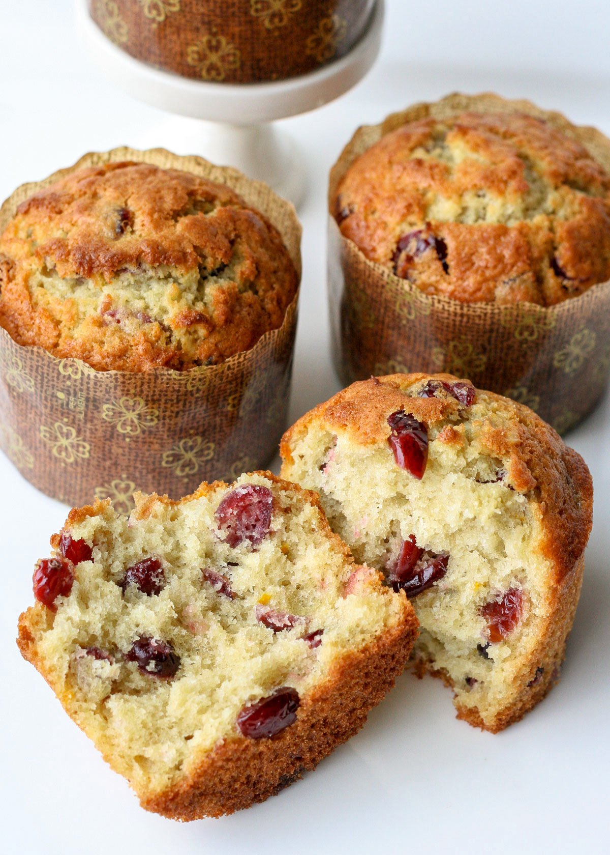 top down view of split cranberry orange muffin with more muffins behind it