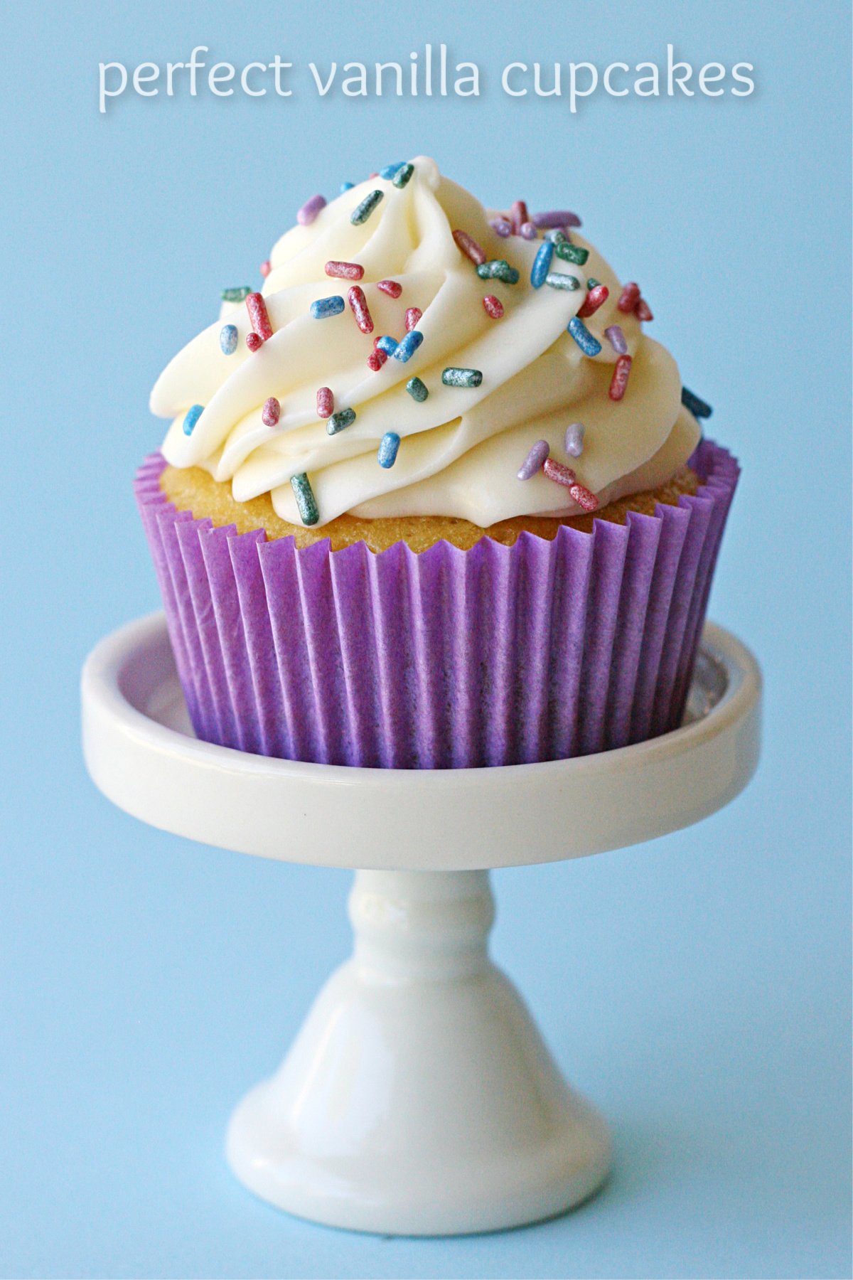 single vanilla cupcake on white cupcake stand with purple liner and pastel sprinkles text overlay at top