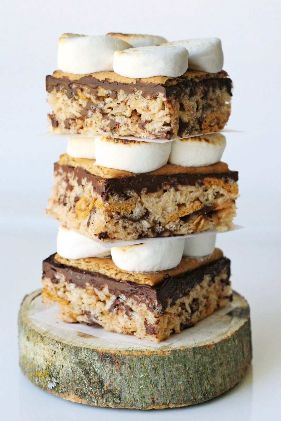 three S'mores rice krispies treats stacked on a small log