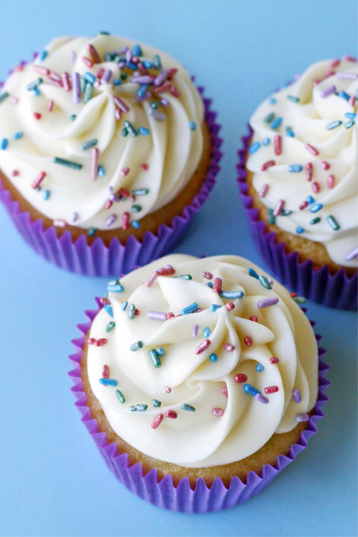 top down view of vanilla cupcakes with white frosting and pastel sprinkles