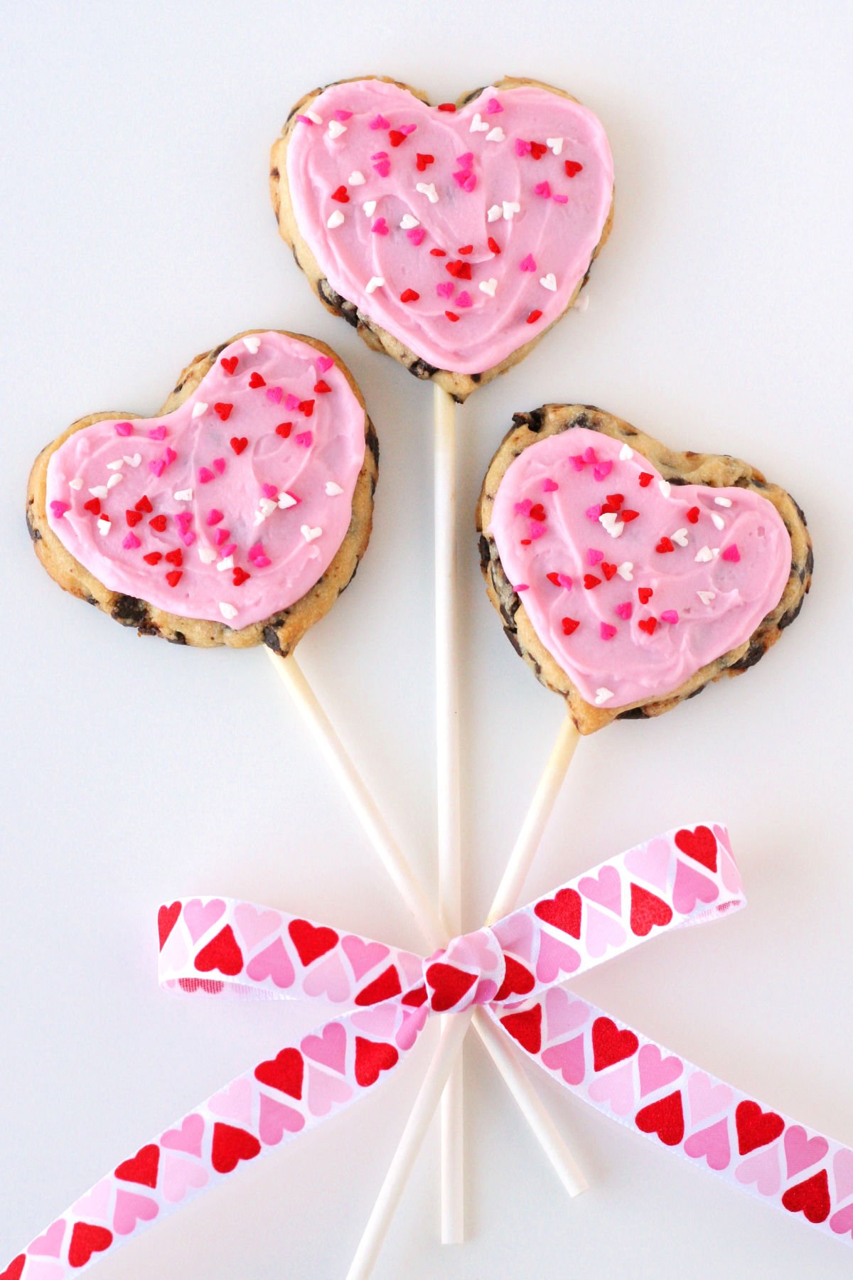 chocolate chip cookie pops with pink frosting and ribbon