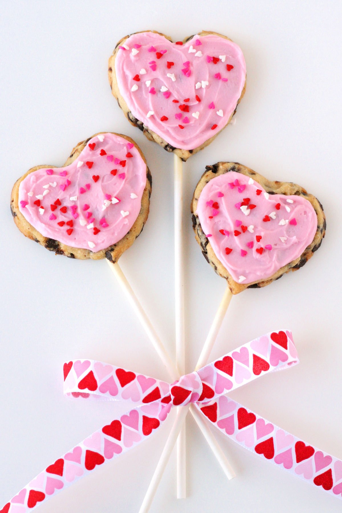 chocolate chip cookie pops with pink frosting and ribbon