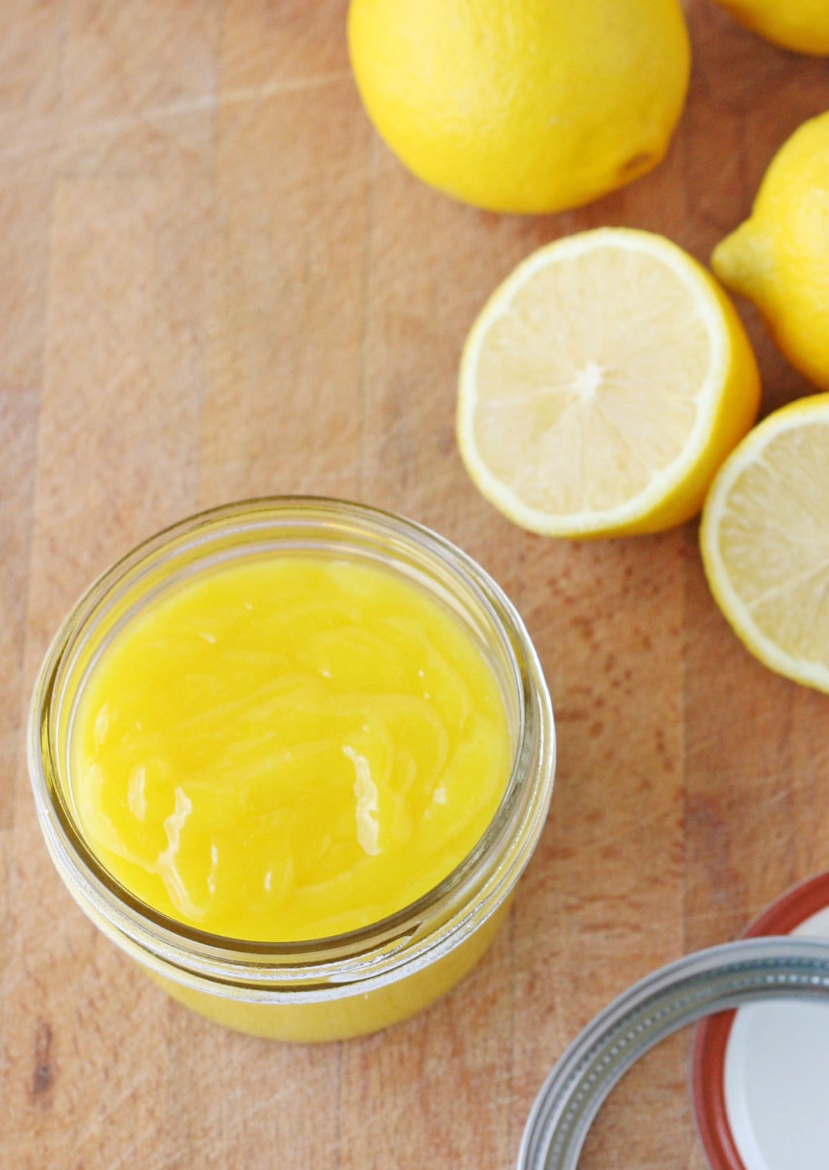 top down view of homemade lemon curd recipe in small jar on wood cutting board