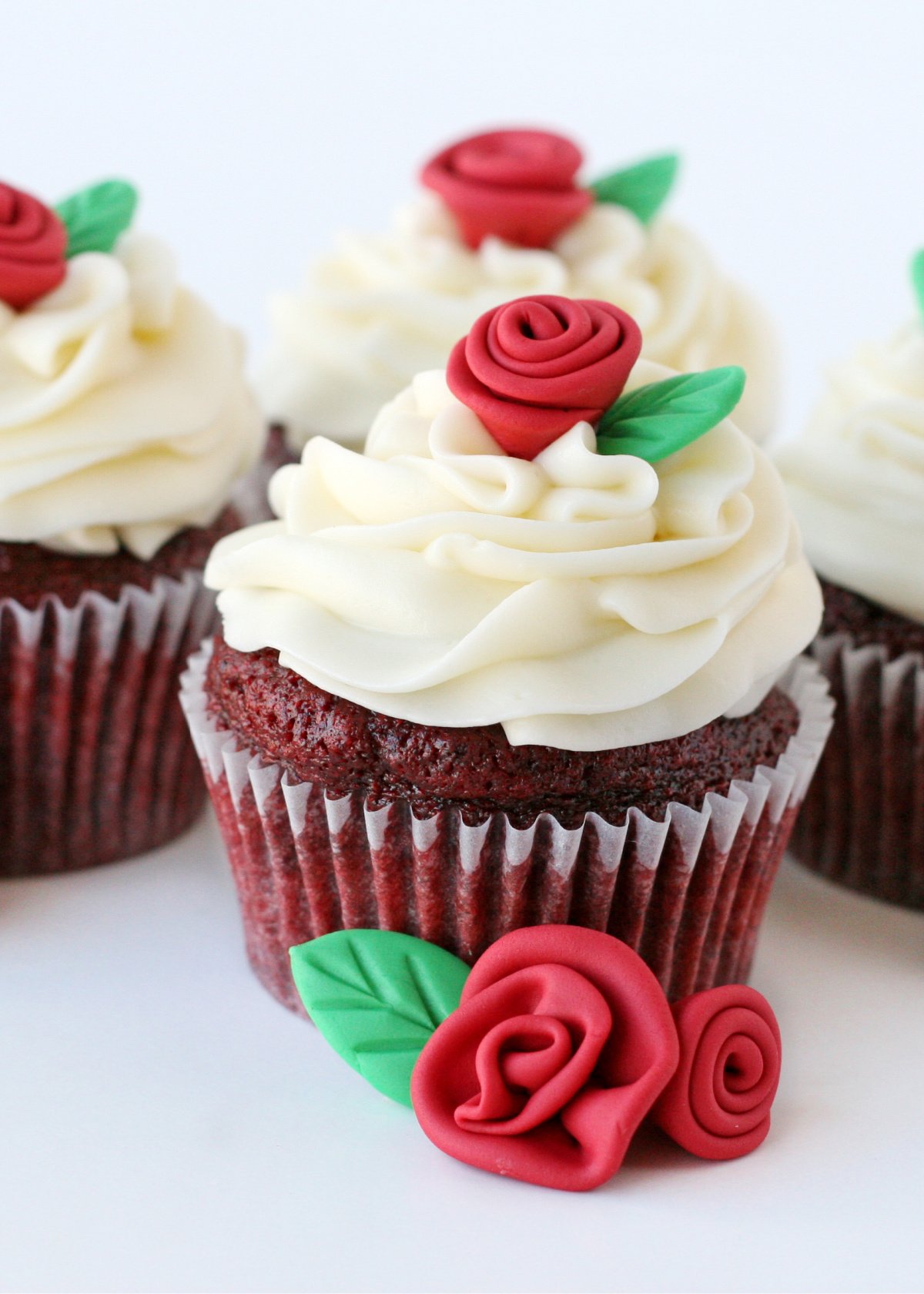red velvet cupcakes on white background with red fondant roses