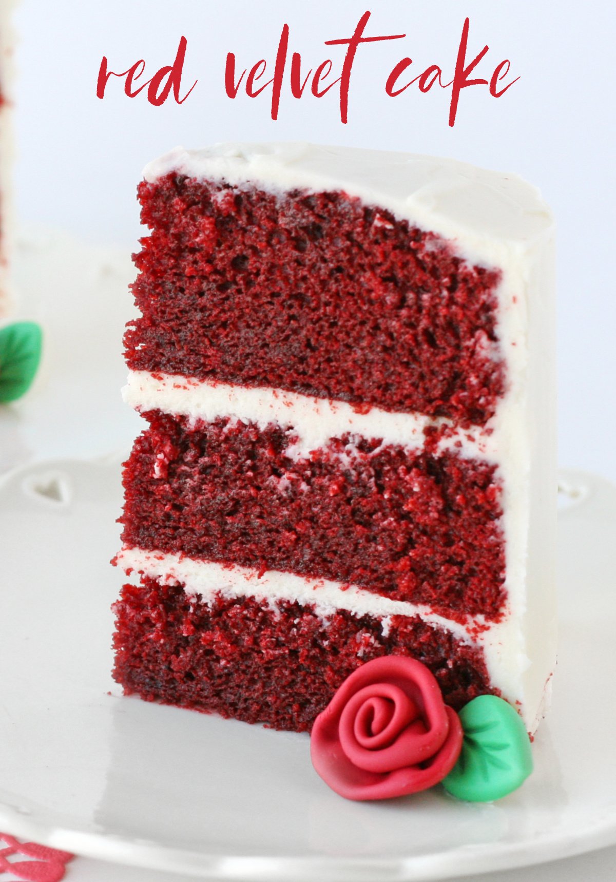 slice of red velvet cake with fondant rose on white plate with text overlay