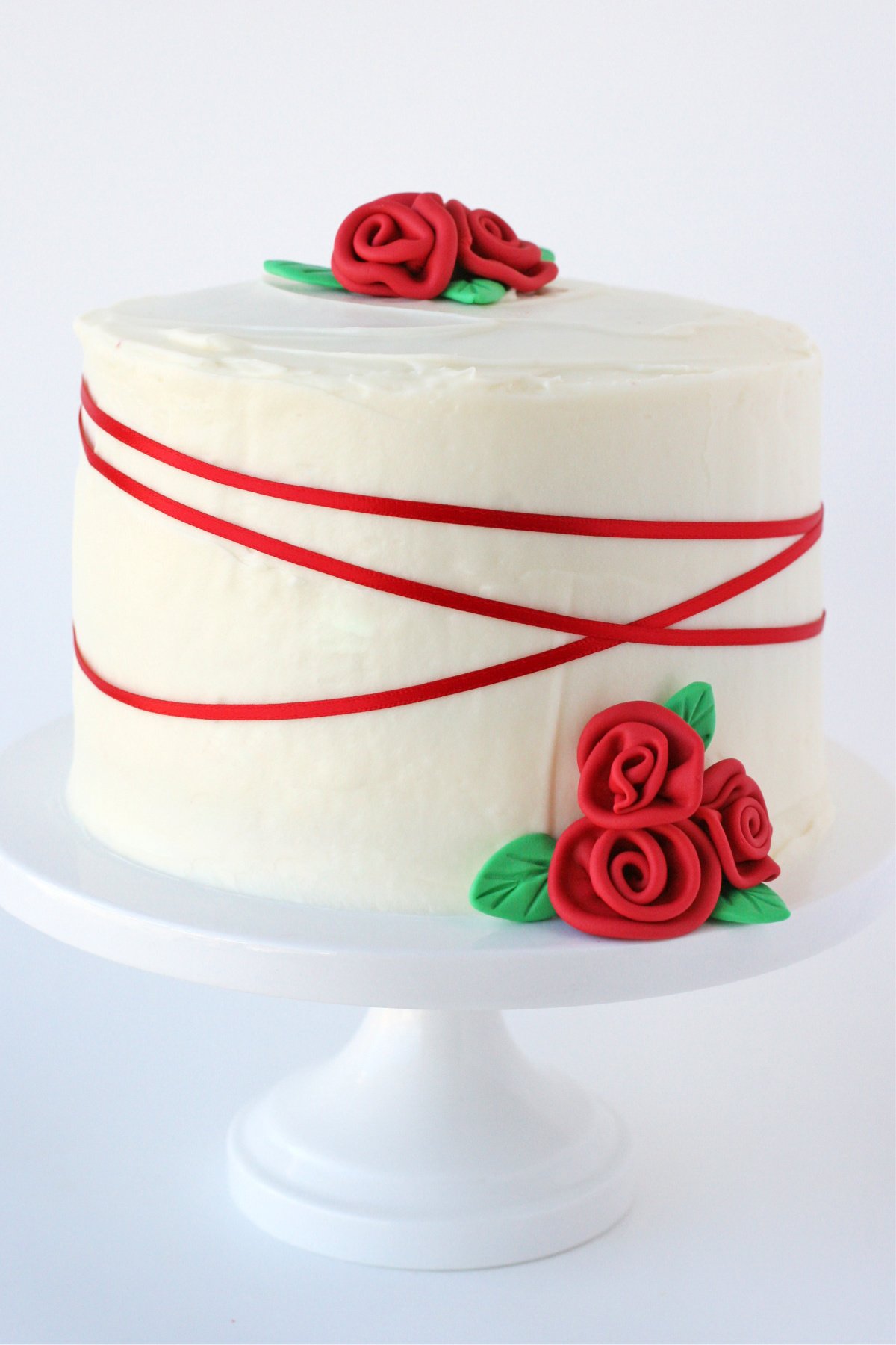 whole red velvet cake recipe on white cake stand decorated with red ribbon