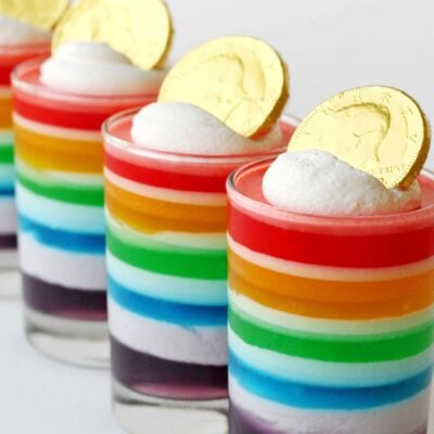 rainbow jello in glasses topped with chocolate coin.