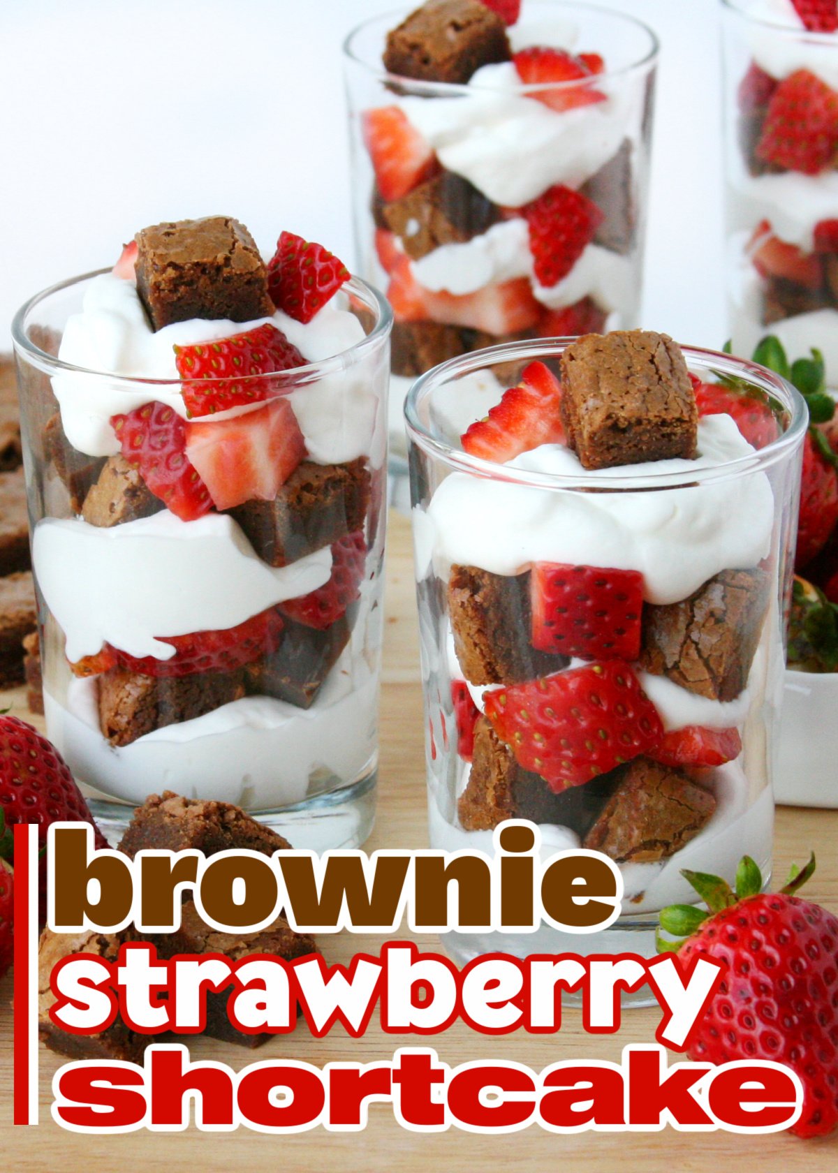 three small glasses with brownies chunks, whipped cream and strawberries layered in them. Title overlay at bottom of image.