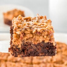 german chocolate brownie being held up with a server over the baking dish full of more brownies.