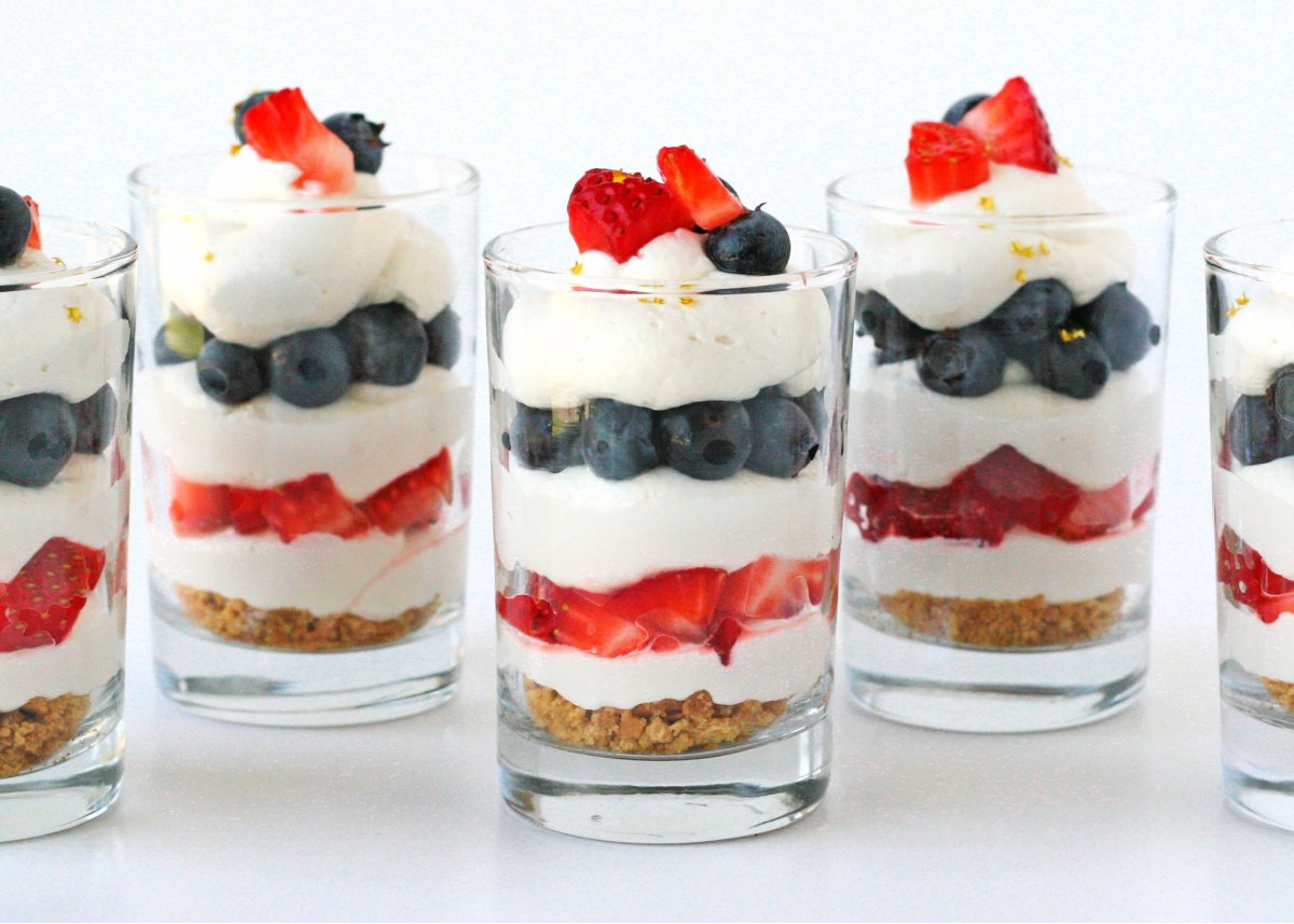 5 glasses with berries and cream and cheesecake.