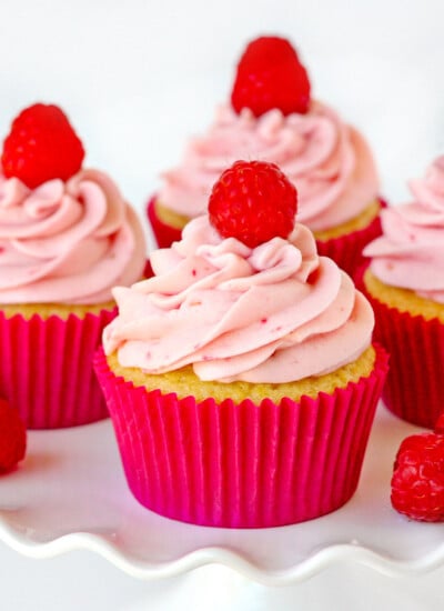 raspberry vanilla cupcakes with raspberry cream cheese frosting on white cake stand