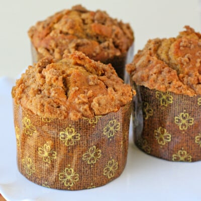 three pumpkin muffins recipe with cinnamon streusel on white cake stand