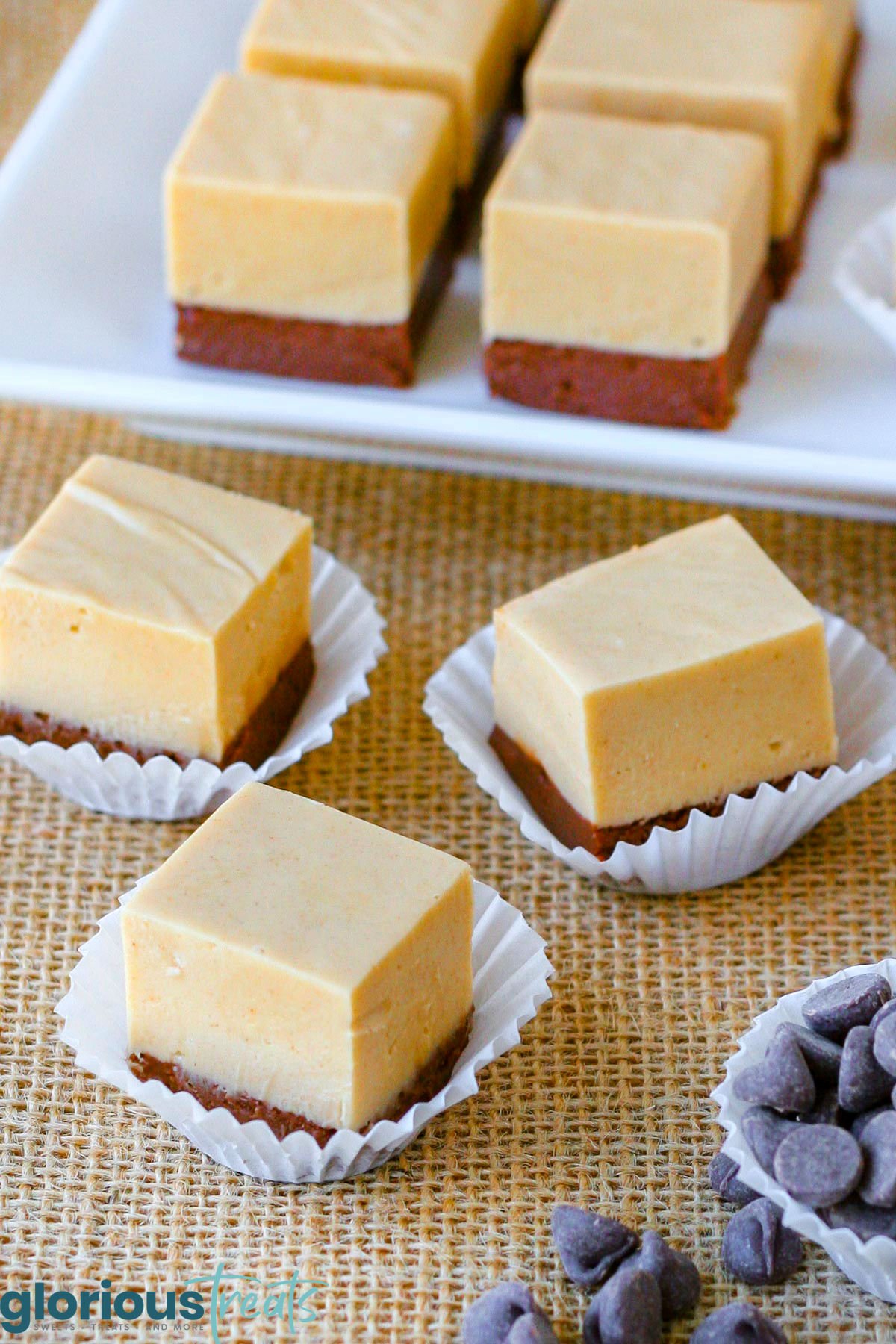 pieces of chocolate peanut butter fudge cut into squares sitting on burlap with more on white tray in background.