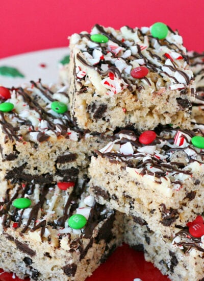 six rice krispie treats made with peppermint oreos and decorated with chocolate and sprinkles on a white plate with a red background.