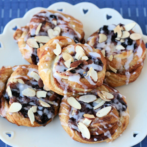 pastries made with puff pastry, cream cheese and blueberry jam drizzled with a glaze and sliced almonds sprinkled on top.