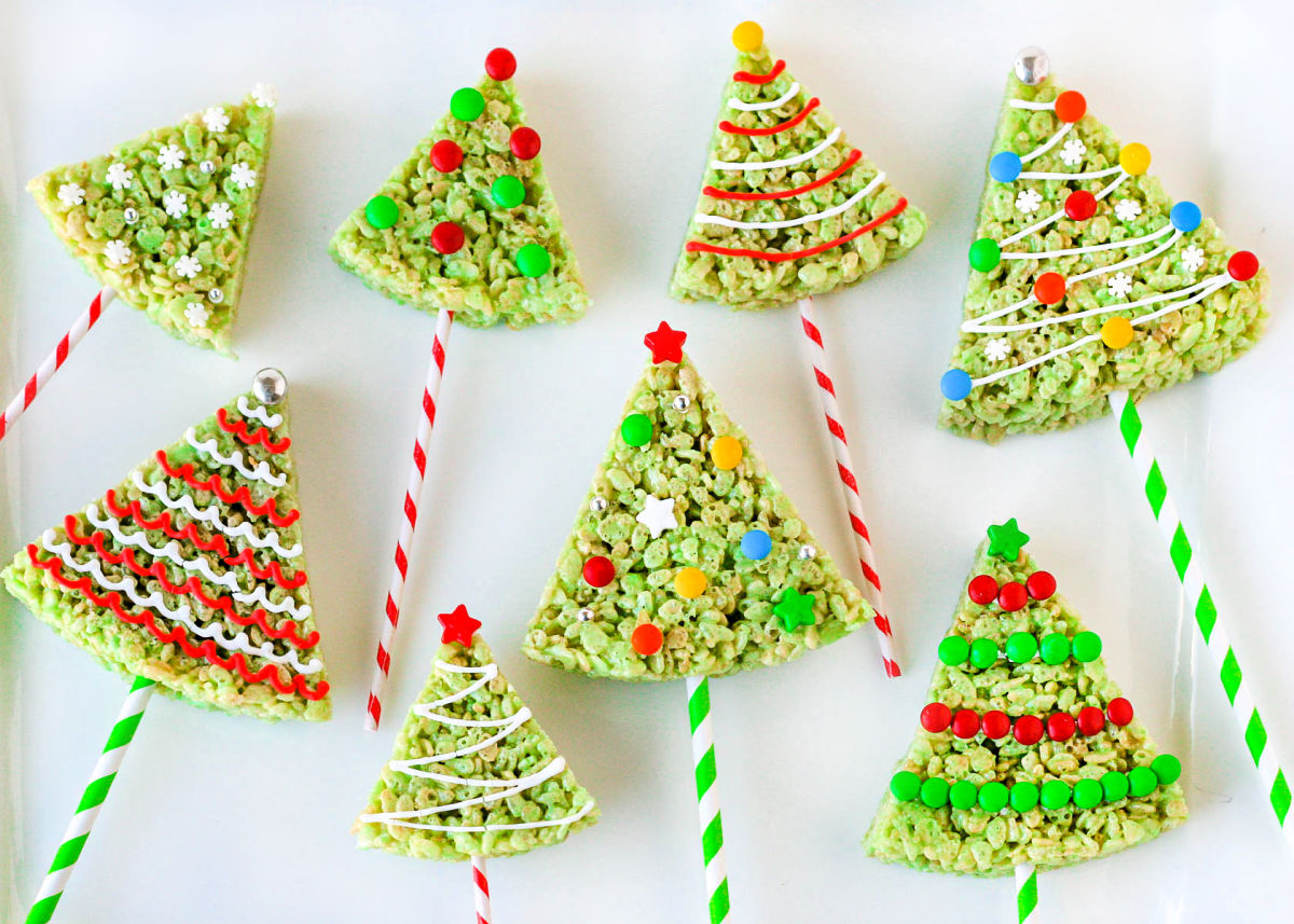 eight christmas tree rice krispie treats laying on a white surface all decorated with candies and frosting.