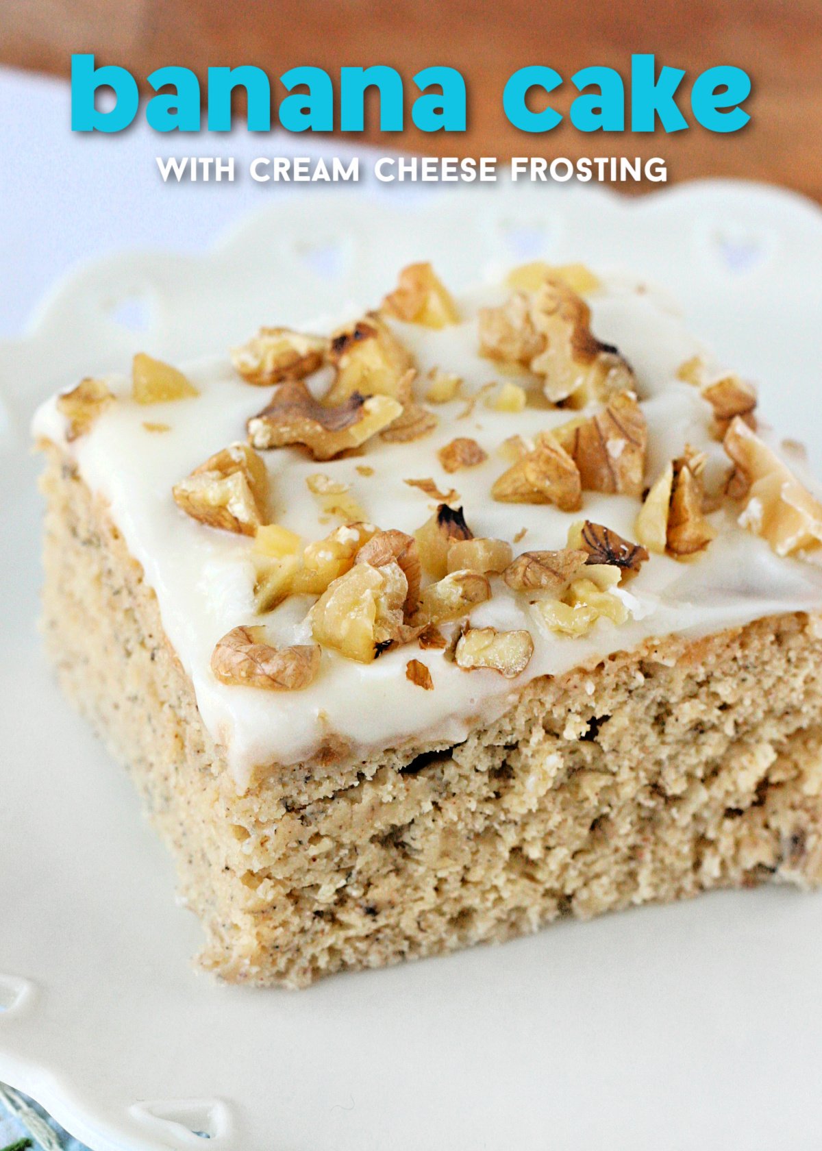 piece of banana cake with cream cheese frosting and walnuts on top sitting on white plate with text overlay at top of image.