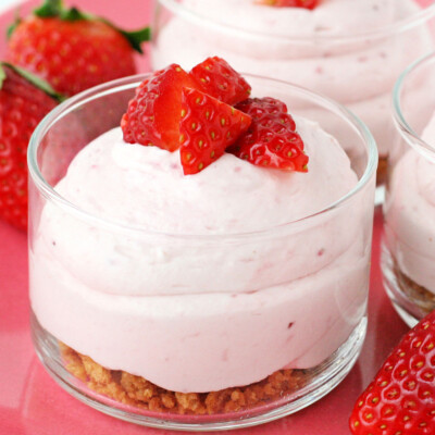 strawberry cheesecake mousse with graham cracker layer in small glass jar topped with fresh diced strawberries square
