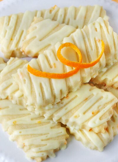 orange sugar cookies on white cake stand.