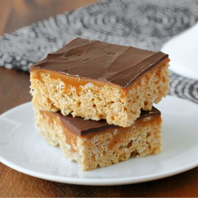 two whatcahmacallit krispie treats sitting on small nondescript white plate in front of cake stand with more treats.