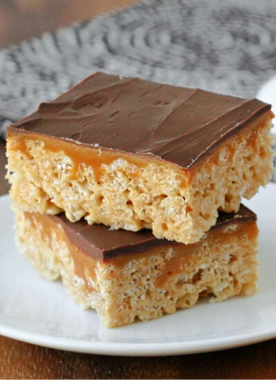 two whatcahmacallit krispie treats sitting on small nondescript white plate in front of cake stand with more treats.