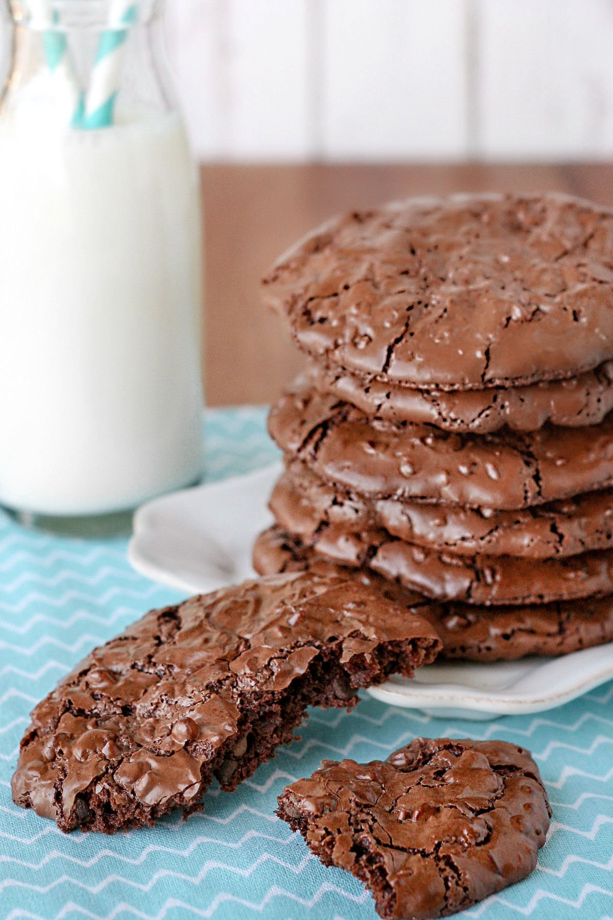 flourless chocolate cookies split in half on blue napkin with stack of cookies in background