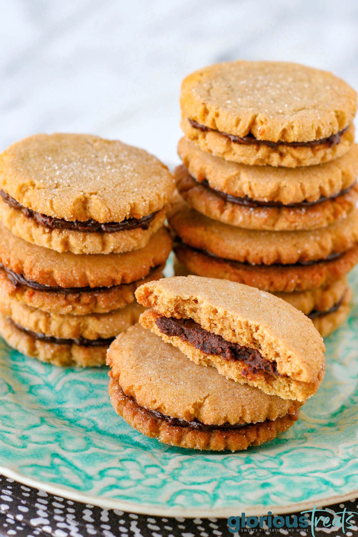 stacks of peanut butter cookies with chocolate filling. front stack's top cookie has been torn in half.