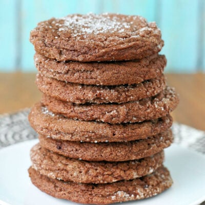 tall stack of chewy chocolate sugar cookies sitting on a round white plate.