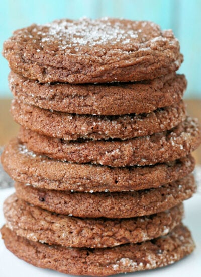 tall stack of chewy chocolate sugar cookies sitting on a round white plate.