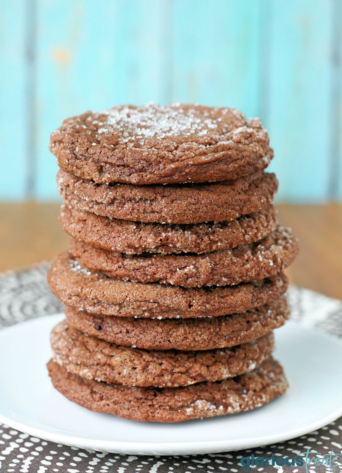 stack of chocolate sugar cookies sitting on a white round plate. 