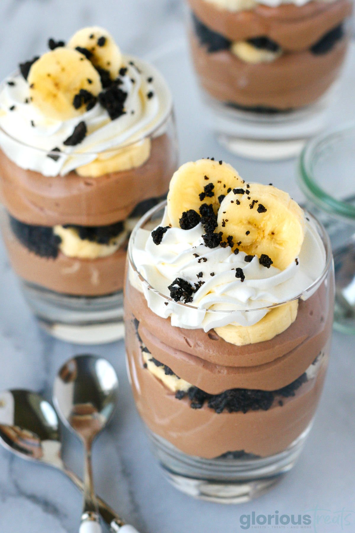 Angled view of three banana oreo nutella trifle in cups. 
