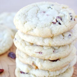 cranberry orange cookies stacked on a wood board