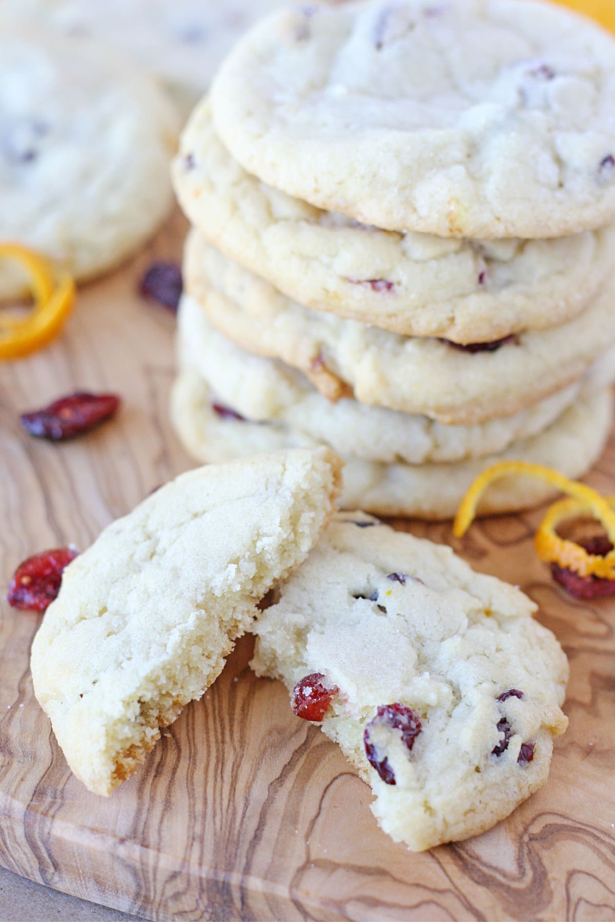 cookie broken in half sitting in front of stack of cookies on a wood board