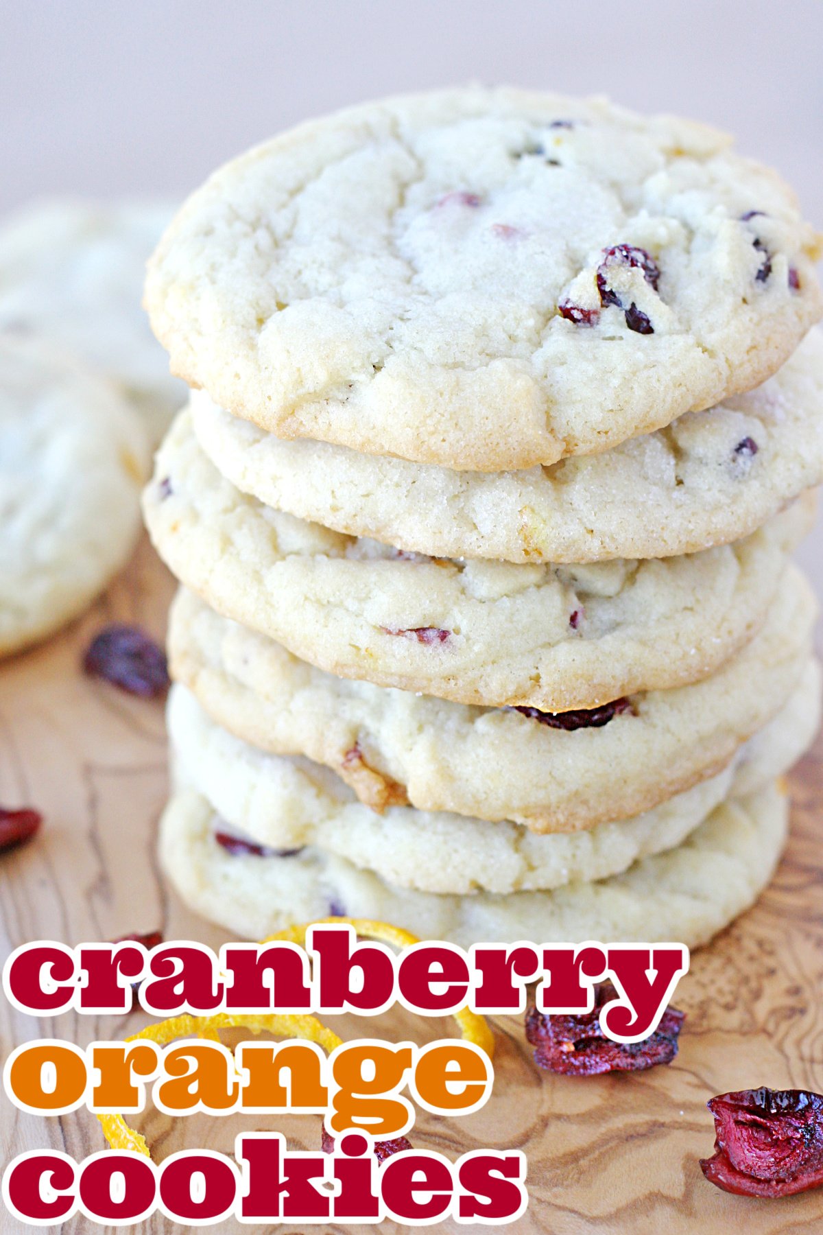 cranberry orange cookies stacked on a wood board with title overlay at bottom