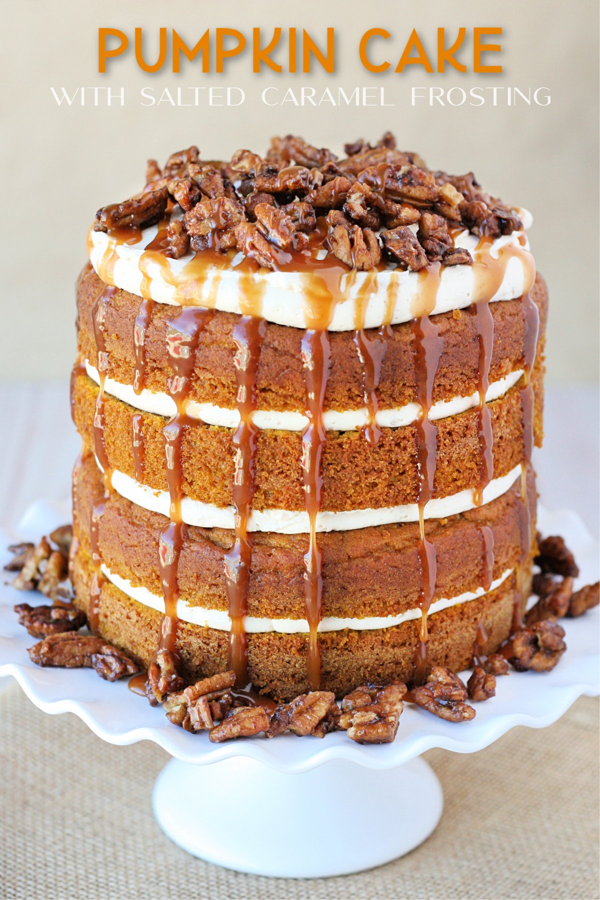 pumpkin layer cake on white cake stand with salted caramel frosting and sauce dripping from the top and covered with candied pecans text overlay at top