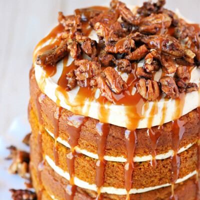 top down view of pumpkin cake with salted caramel frosting on white cake stand with candied pecans on top