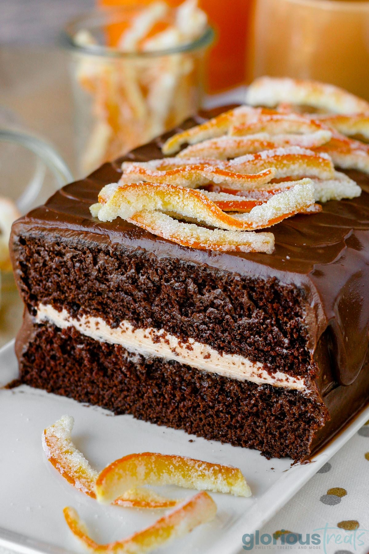 Cross section view of two layer chocolate cake with orange frosting and chocolate ganache frosting. Topped with candied orange peels.