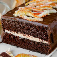 Tall graphic of chocolate orange cake shown on serving platter topped with candied orange peel. Text overlay at top and bottom of image.