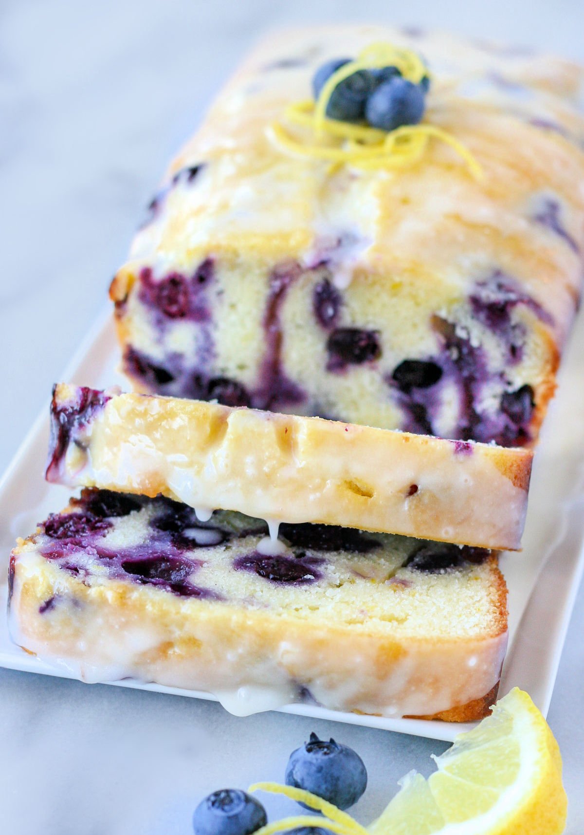 lemon blueberry bread recipe on white plate with two slices cut