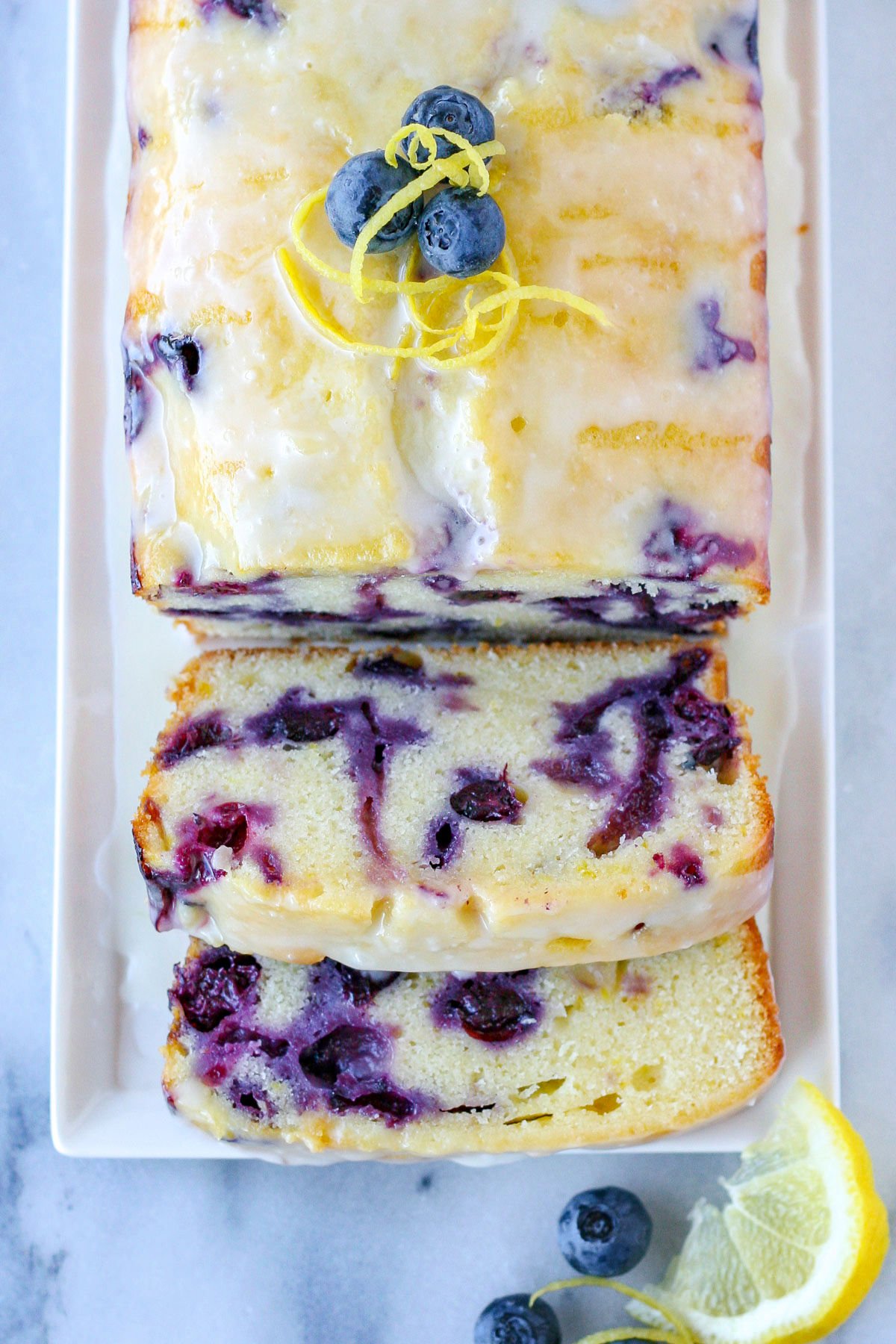 top down view of loaf of lemon blueberry bread on white plate