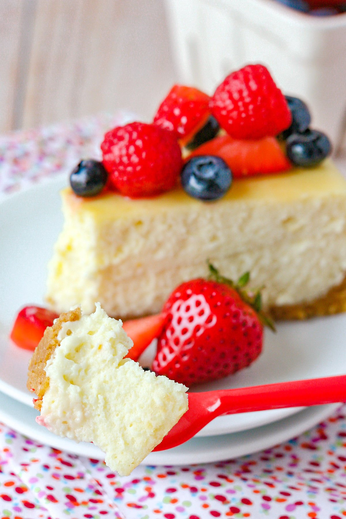 cheesecake slice on plate with one bite on fork.